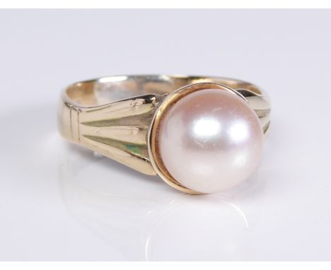 A 9ct yellow gold and cultured pearl ring: marked '9CT', the 9mm. pearl in a cup setting over trifurcated shoulders, size P½.