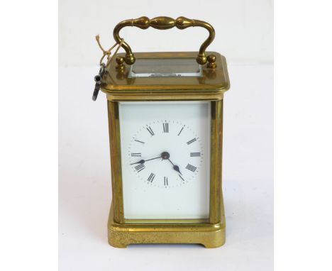 An early 20th century brass and glass-sided carriage clock: white-enamel dial with Roman numerals and blued steel hands, the 