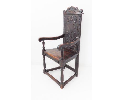 A wainscot chair in 17th century style (probably 19th century): the scrolling crest rail centred with a carved tulip above a 