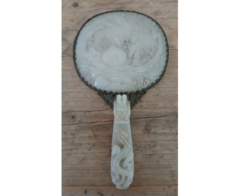 An early 20th century Chinese carved jade and gilt metal mounted hand mirror, the 18th/19th century celadon jade panel carved