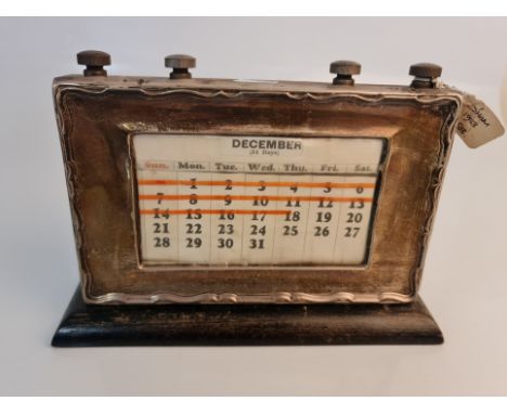 A silver desk calendar on wood base