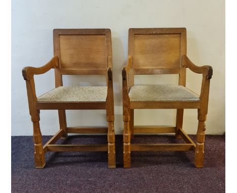 A pair of Robert Thompson Mouseman oak carved dining chairs.