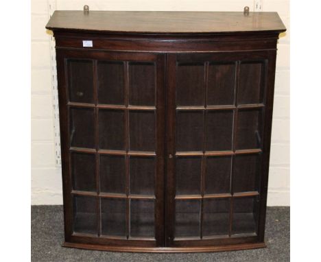 An Edwardian mahogany wall mounting collector's cabinet of slight bow front form, having a pair of glazed doors enclosing sin