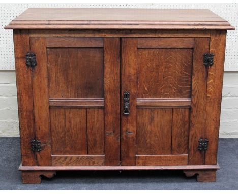 An early 20th century oak cupboard, the rectangular caddy top over two panelled doors, enclosing a single shelf, on bracket f