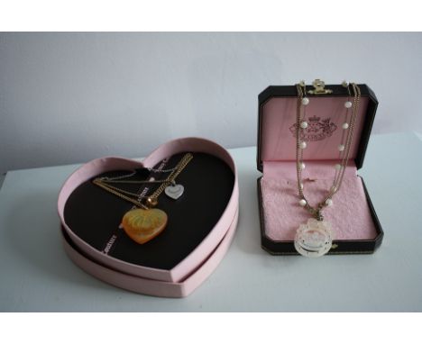 2 Juicy Couture necklaces, boxed. A short triple strand pendant with pearls.A multi-strand charm necklace, with large heart, 