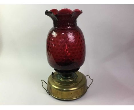 BRASS AND GLASS OIL LAMP, EARLY 20TH CENTURY the dimpled ruby glass shade with leaf formed rim, enclosing a glass funnel and 