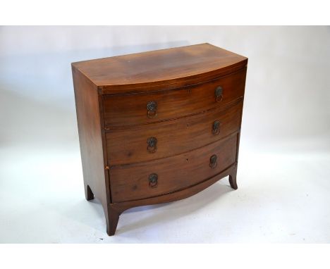 A 19th century mahogany bow-front chest of three long graduated drawers, with later brass mask and ring pulls, raised on spla