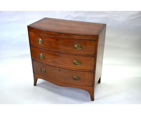 A George III cross-banded mahogany bowfront chest of three long graduated drawers, with later oval brass fittings, raised on 
