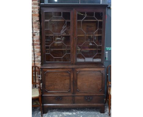 A 19th century mahogany astragal-glazed bookcase cabinet over a pair of cupboards and two short drawers, raised on shaped bra