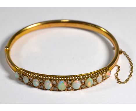 An oval opal and diamond half-hinged bangle, the nine oval graduated cabochon opals each with two diamonds between, yellow go