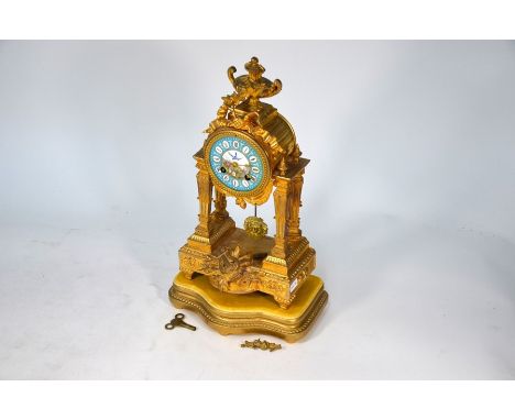 An antique gilt spelter portico mantle clock, the 8-day movement with white enamelled dial striking on a bell, raised on a gi