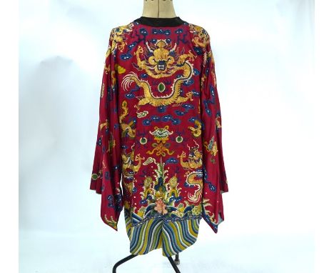 A late 19th century Chinese crimson ground silk 'dragon' robe, Jifu, the long side fastening robe richly embroidered with a d