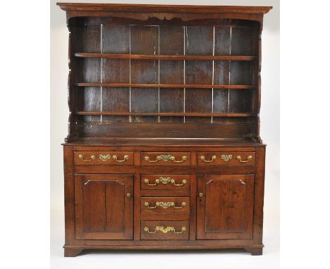 A George III oak dresser with rack, North Wales, the later three tier rack above a base with three frieze drawers above three