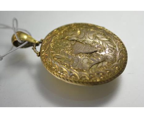 A large Victorian yellow metal (unmarked) locket, oval, engraved with ferns and foliage, enclosing two glazed portrait panels