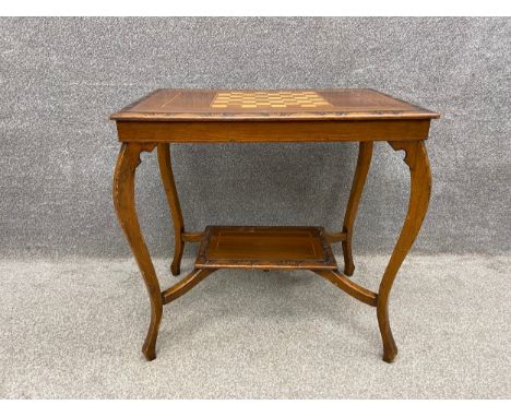 A late 19th century walnut chess table with an inlaid satinwood board and a moulded and carved edge over a small lower shelf 