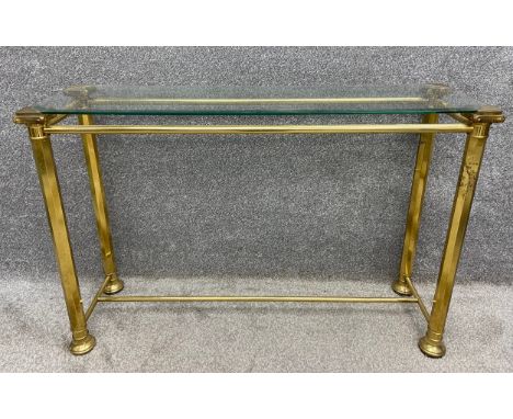 A mid-century Hollywood Regency style brass console table with a plate glass top on four stretchered column supports. H.76 W.