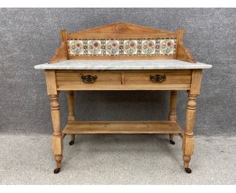 A late 19th century pitch pine wash stand with a raised and shaped gallery back inset with Art Nouveau tiles on a white veine