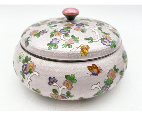A Korean .99 silver and enamel round cloisonné box with a scrolling foliate and floral design with butterflies over a pink gr