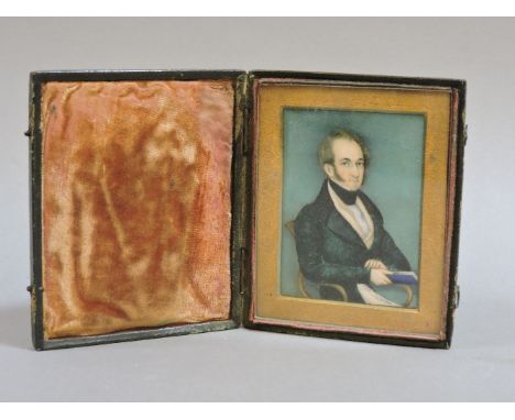 A portrait miniature, of a Regency gentleman seated with a book, mounted in a leather case, 9 x 6.5cm