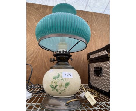 A SMALL BRASS AND CERAMIC OIL LAMP CONVERTED TO ELECTRIC AND COMPLETE WITH GREEN GLASS SHADE 