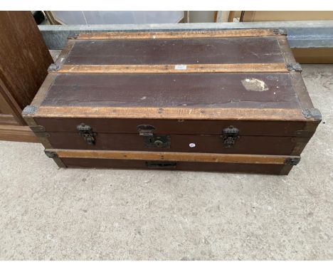 AN EDWARDIAN COMPRESSED FIBRE AND BANDED TRAVELLING TRUNK 