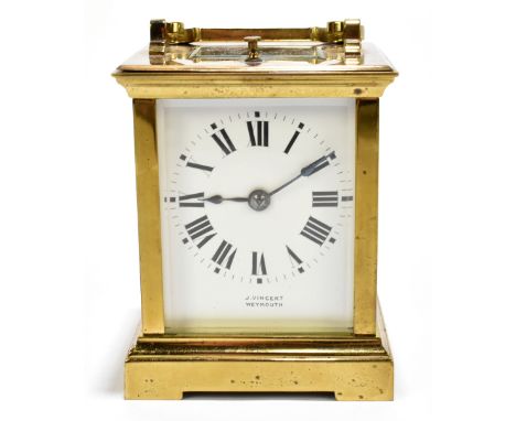 A circa 1900 brass repeating carriage clock with swing loop handle above white enamel dial set with Roman numerals inscribed 