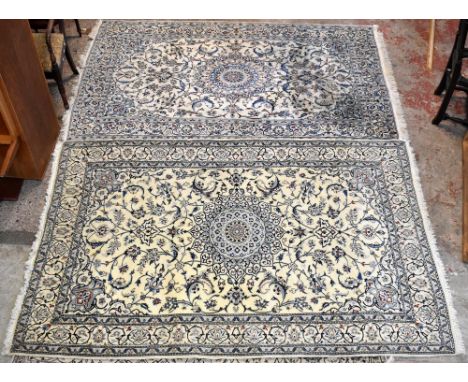 Two similar modern Persian rugs each with central and stylised circular medallion within a cream ground main panel and floral