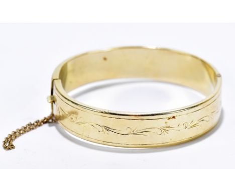 A yellow metal snap bangle with chased scrolling detail, stamped 14K, approximate weight 24.37g.&nbsp;Additional InformationL