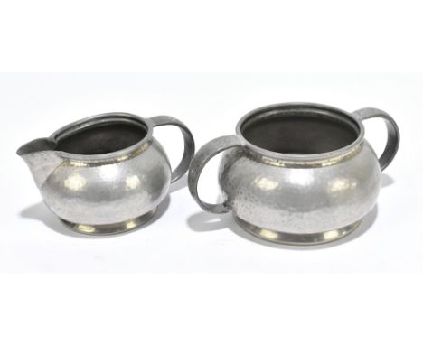 TUDRIC PEWTER; a twin handled sugar bowl and matching cream jug each with planished decoration, numbered 01075 (2).Additional