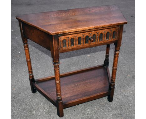 A reproduction oak side table, the single drawer with carved decoration above undertier shelf, raised on block feet, width 86