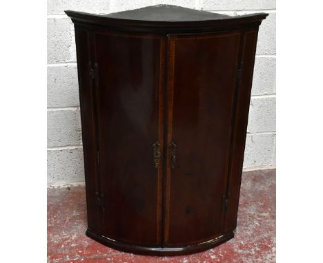 A George III mahogany bowfront corner cabinet, with two doors enclosing shelves and three drawers, height 111cm, width 76.5cm