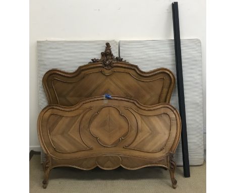 A French walnut framed double bedstead in the Louis XV taste, the headboard with scrolling foliate surmount, 214 cm long x 15