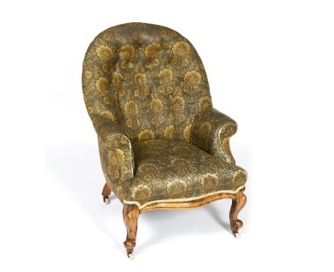 A VICTORIAN WALNUT FRAMED ARMCHAIR, with button backed green upholstery, on cabriole legs and castors