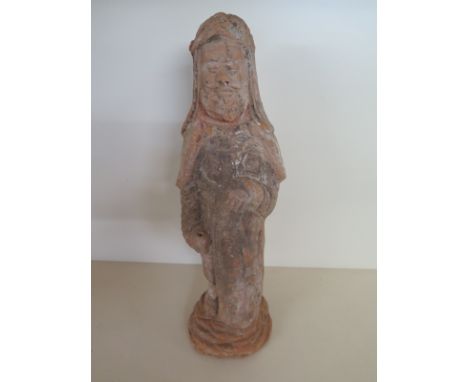 A painted pottery figure of a soldier Tang dynasty standing with one hand resting on the shield, the head under a helmet, wea