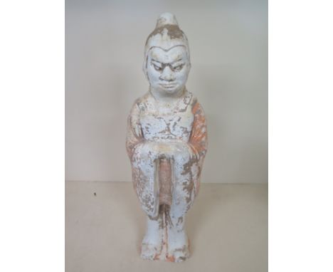 A painted pottery figure of a guard Tang dynasty dresses in a long garment, the hands clasped in front of the breast, with fl