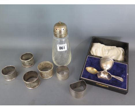 A silver egg cup and spoon boxed, six silver serviette rings and a silver top glass shaker - one serviette ring Indian silver