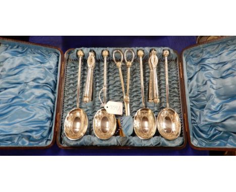 A cased EPNS nut cracker, grape scissor and serving spoon set, with embossed scrolling foliate decoration Condition Report:Av