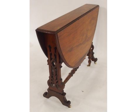 A Victorian rosewood topped drop leaf table with carved fretwork supports terminating in ceramic casters Condition Report:Ava