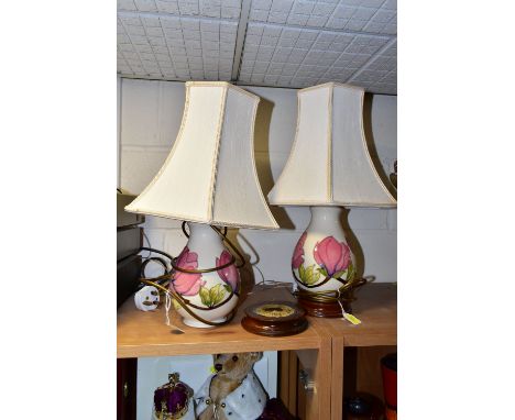 A PAIR OF MOORCROFT POTTERY TABLE LAMPS, comprising two pink magnolia on cream ground lamp bases with  wheat coloured shades,