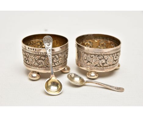 A PAIR OF LATE VICTORIAN SILVER SALTS, each decorated with an embossed floral pattern with vacant cartouche, worn gilt interi