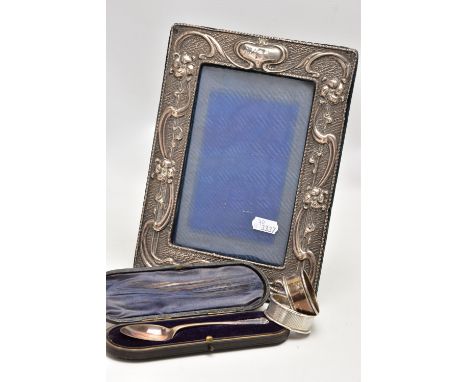 AN EDWARDIAN SILVER PHOTO FRAME, TWO NAPKIN RINGS AND A CASED TEASPOON, the rectangular photo frame with embossed floral desi