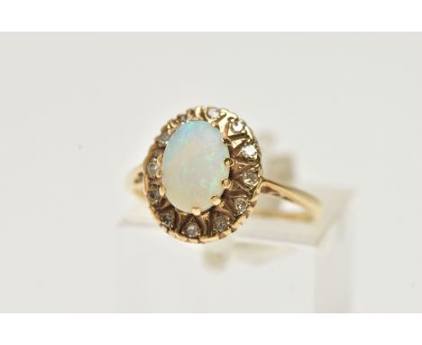 A YELLOW METAL, OPAL AND DIAMOND CLUSTER RING, of an oval form, centring on an oval opal cabochon, raised in a surround of si