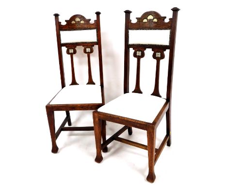 A pair of late 19thC Art Nouveau oak chairs, with arched top rails, compressed square finials and overstuffed backs and seats