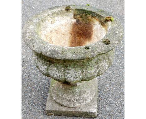 A classical urn stone garden planter, the bellied gadrooned body, on an inverted stem with a circular foot and square plinth 