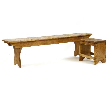 An early 20th century pine bench, the rectangular plank top on end supports, 168cm long, together with a similar stool (2)