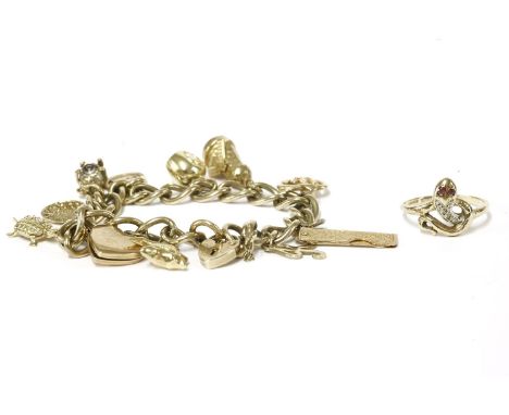 A gold charm bracelet with 9ct gold padlock and eleven assorted charms, to include a New York apple marked 585, a 'K' initial