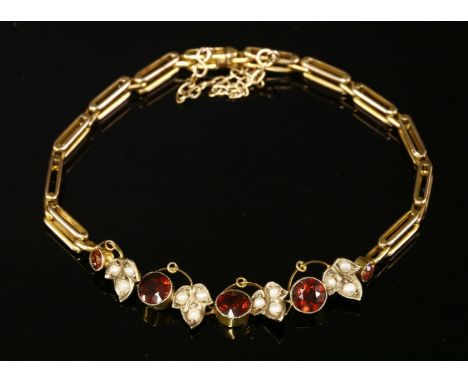 An Edwardian garnet and split pearl bracelet, c.1910, with a centrepiece composed of a series of circular graduated mixed cut