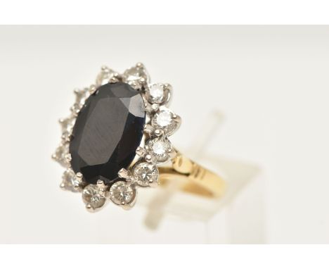 AN 18CT GOLD LARGE SAPPHIRE AND DIAMOND CLUSTER RING, of an oval form, set with a central oval cut deep blue sapphire, measur
