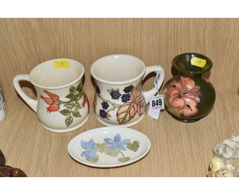 A GROUP OF MOORCROFT CERAMICS to include two mugs comprising a 'Rosehip' patterned mug and a 'Blackberry' patterned mug, a 'H