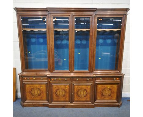 A 20TH CENTURY MAHOGANY AND WALNUT BREAKFRONT BOOKCASE, fitted with four bevelled glass doors, atop a base with four drawers,